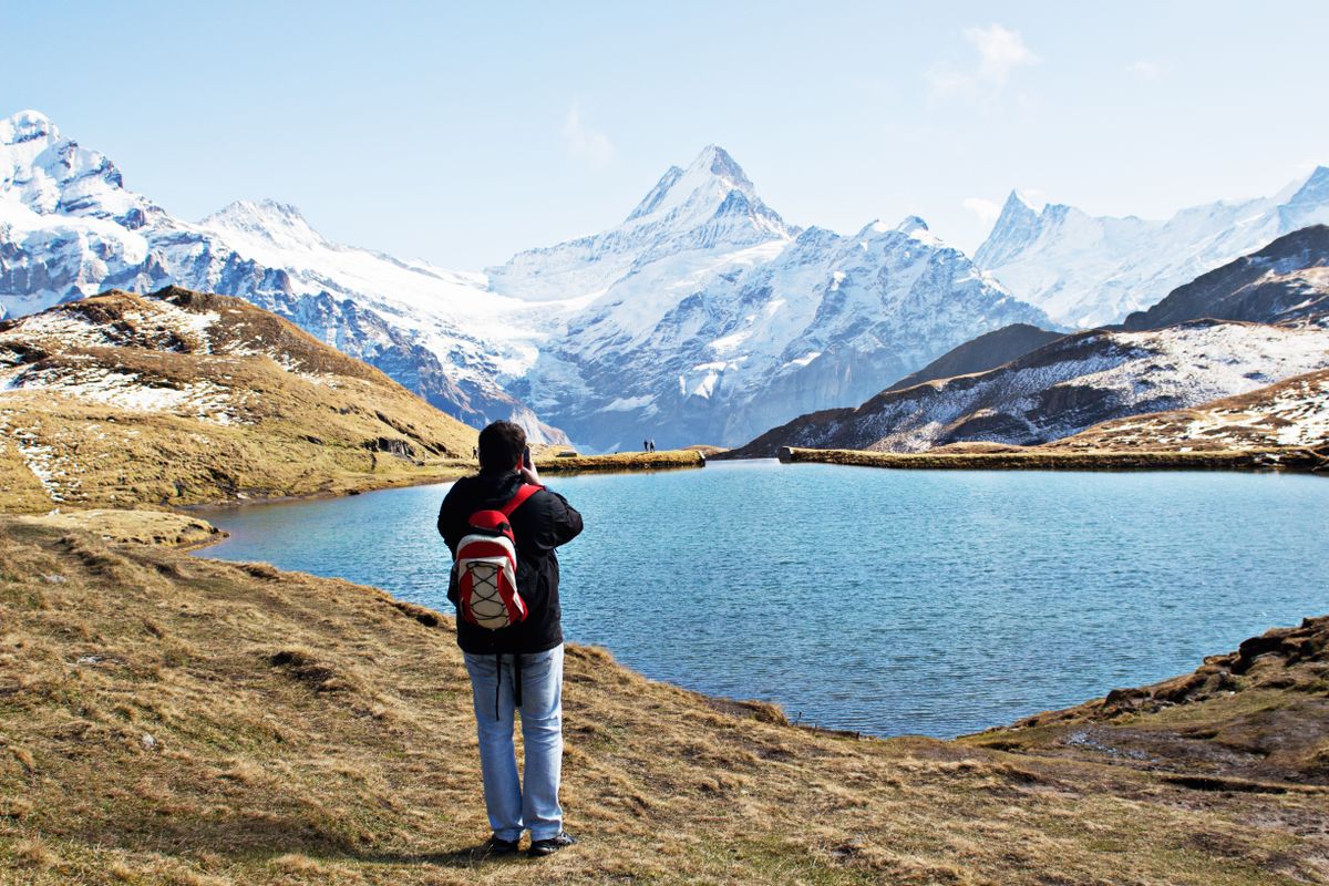 Excursionista con mochila frente a un lago y montañas nevadas en Grindelwald, Suiza
