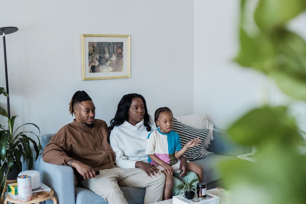 Una familia sentada en el sofá viendo televisión