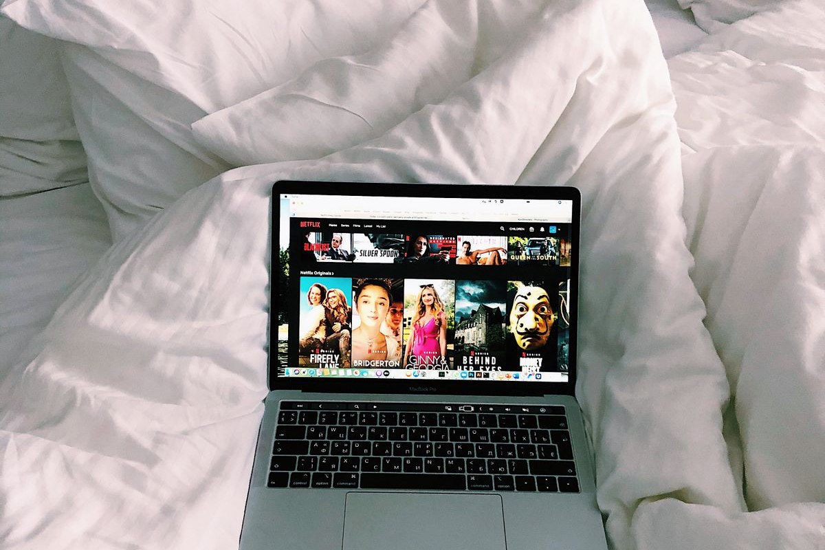 Laptop sobre una cama con una plataforma de películas en la pantalla