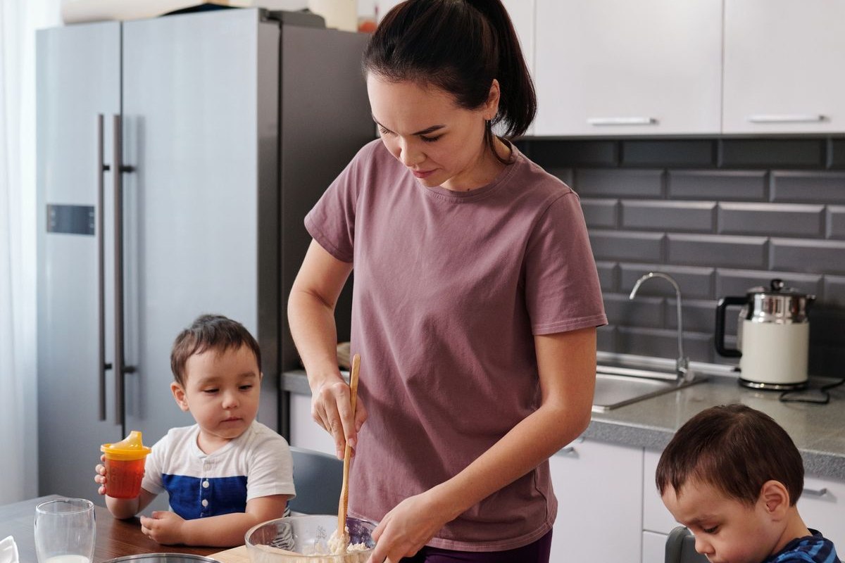 Una mujer preparando comida en la cocina con dos niños