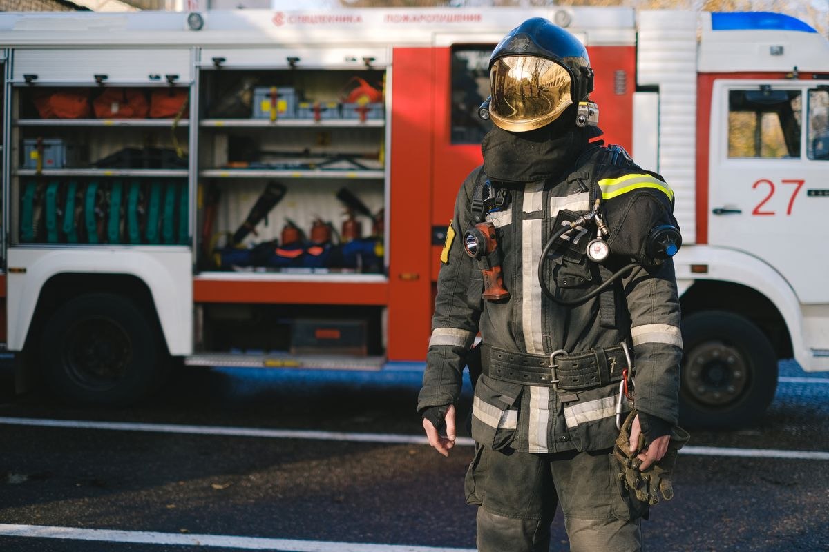 Bombero con uniforme y casco junto a un camión de bomberos