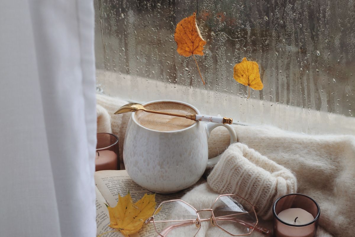 Taza caliente junto a una ventana mojada por la lluvia