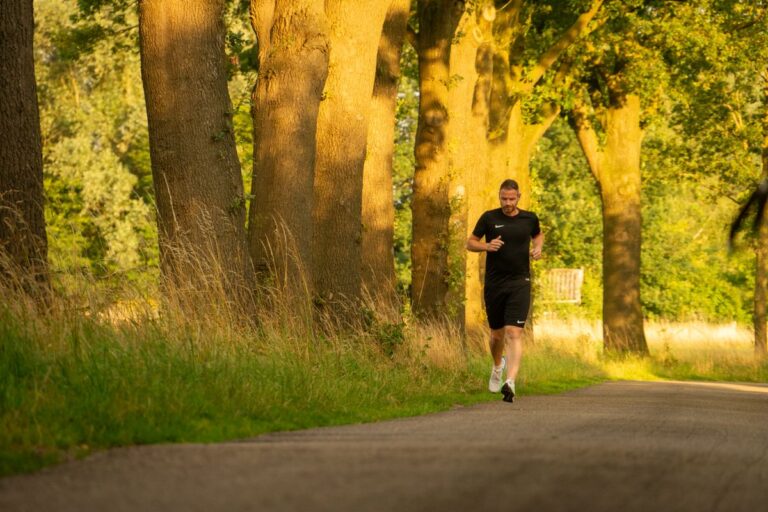 Hombre corriendo por un sendero soleado en un parque