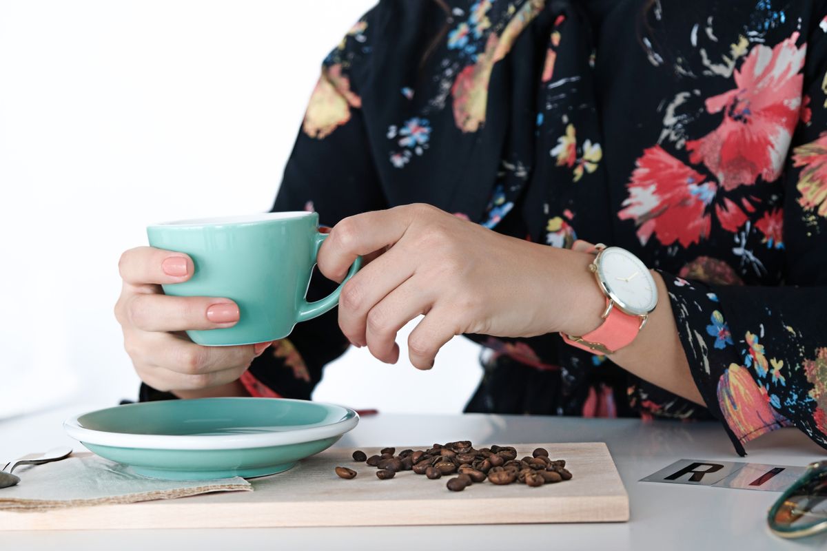 Mujer con una taza de café y un reloj sobre la mesa