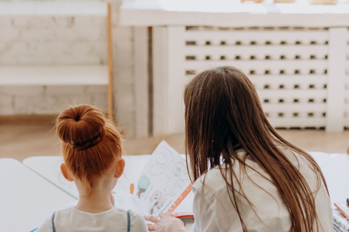 Madre ayudando a su hija con la tarea en la mesa