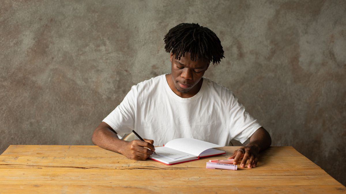 Estudiante escribiendo en un cuaderno durante una sesión de estudio