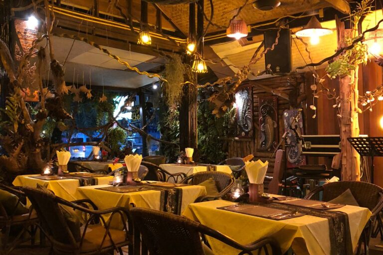 Interior de un restaurante pequeño con mesas de madera y plantas