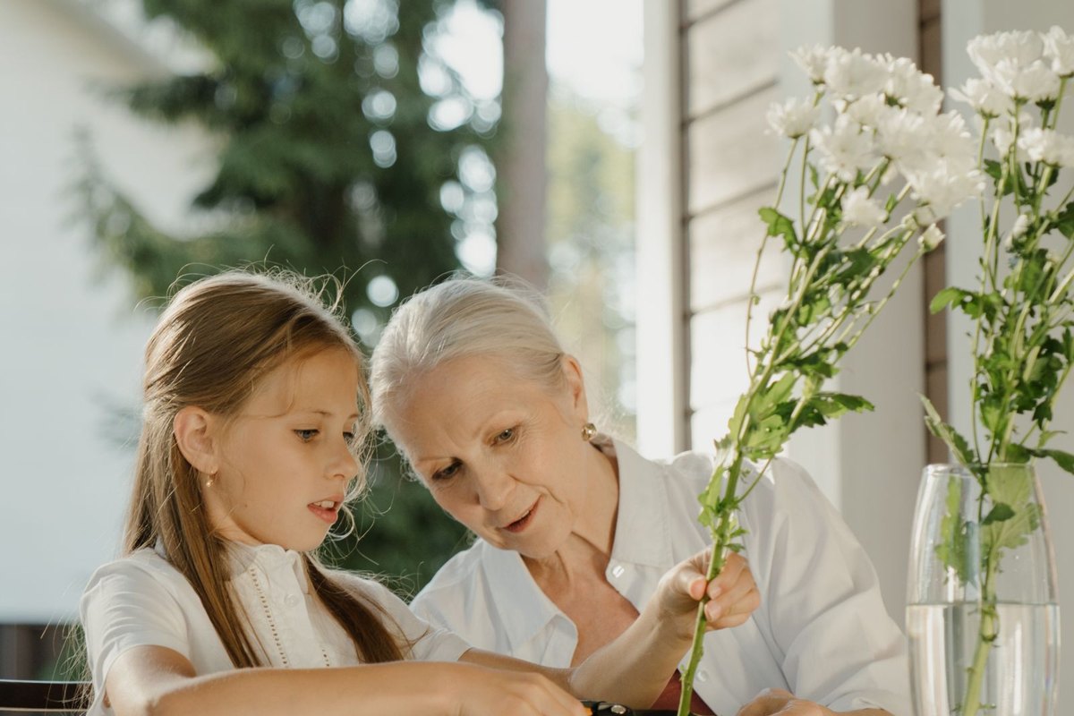 Abuela y nieta preparando flores en una mesa al aire libre