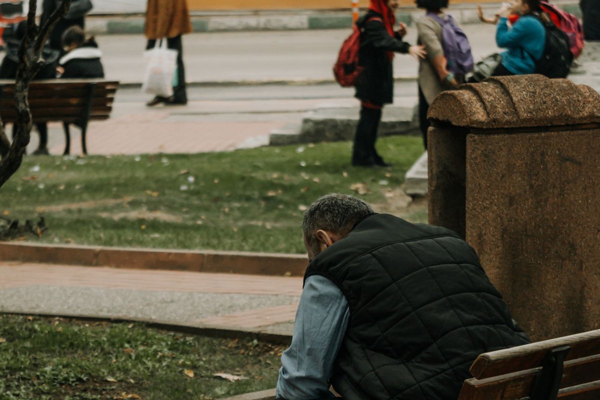 Hombre sentado solo en un banco de un parque