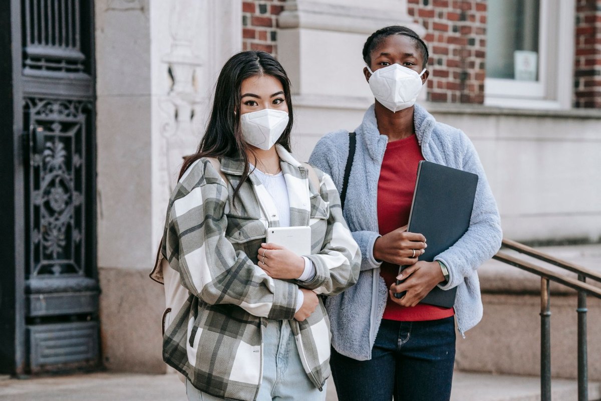 Estudiantes con cuadernos y una laptop junto a un edificio universitario