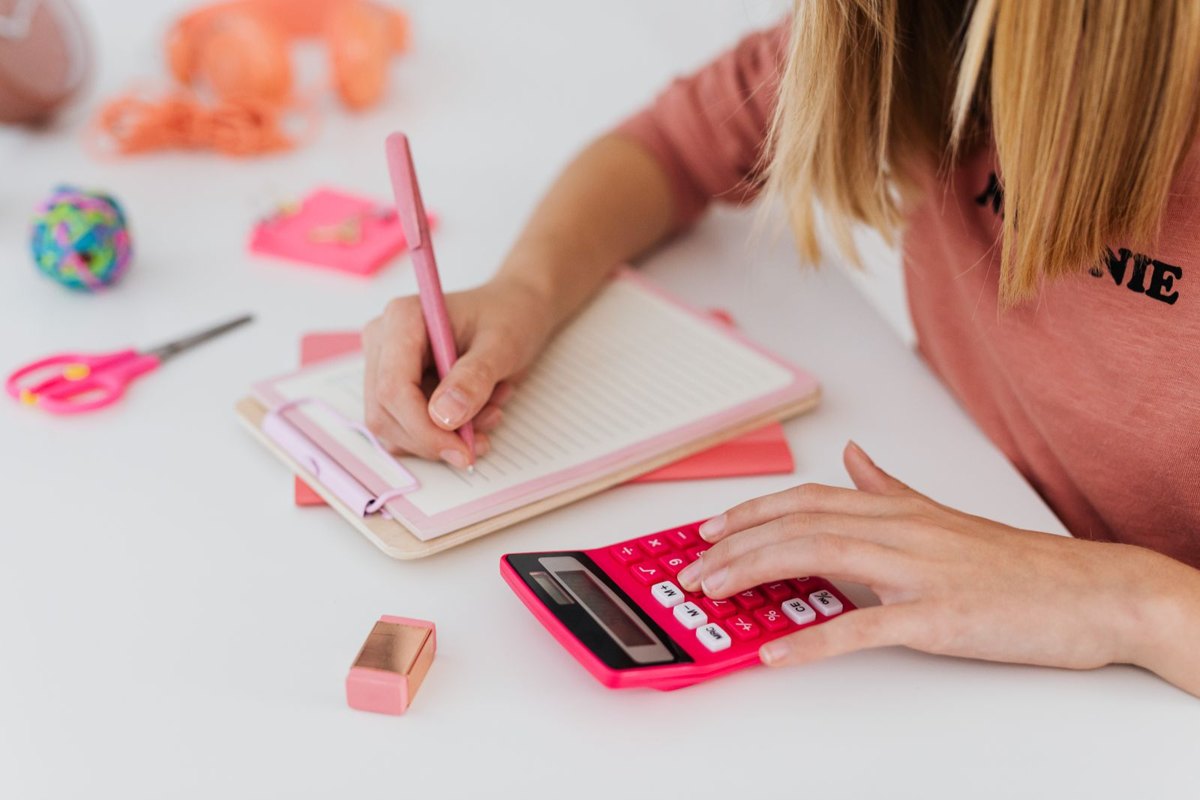 Estudiante resolviendo problemas en un cuaderno junto a una calculadora