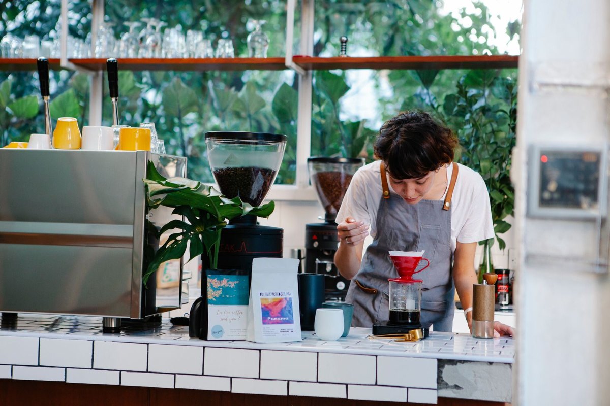 Barista preparando café detrás del mostrador de una cafetería pequeña